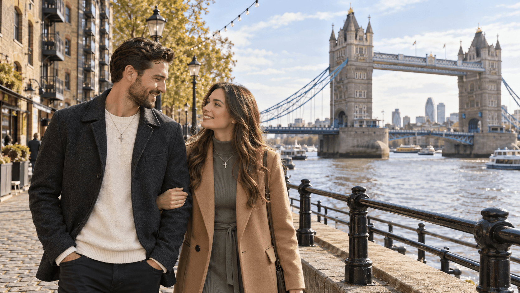 Couple wearing cross necklaces beside the Thames in London, with Tower Bridge in the background.