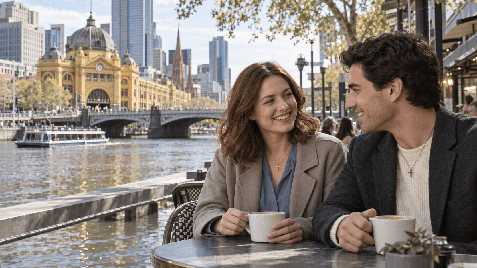 Couple wearing cross necklaces beside the Yarra River in Melbourne, with Flinders Street Station in the background.