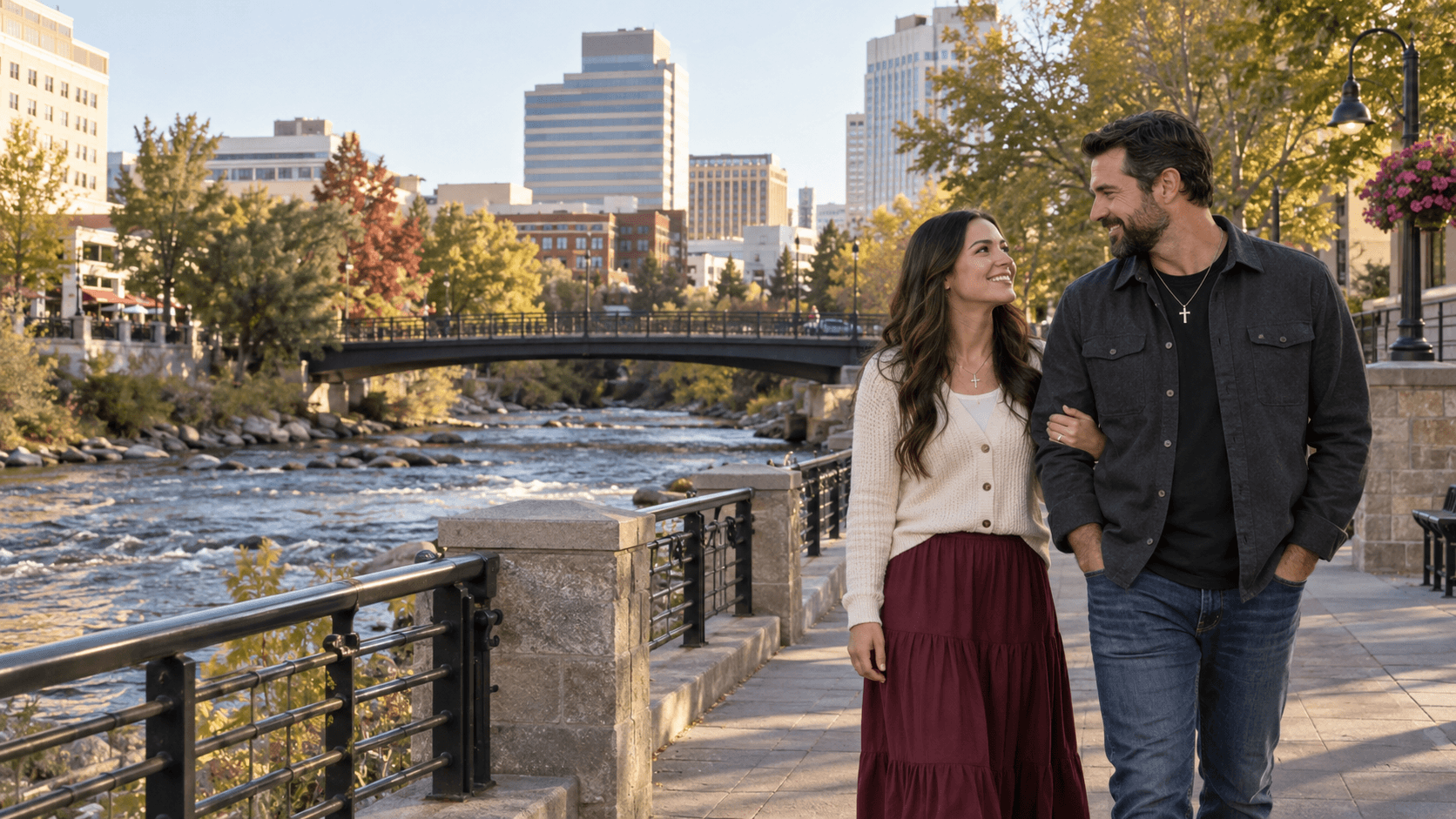 Couple wearing cross necklaces beside the Truckee River with downtown Reno in the background.