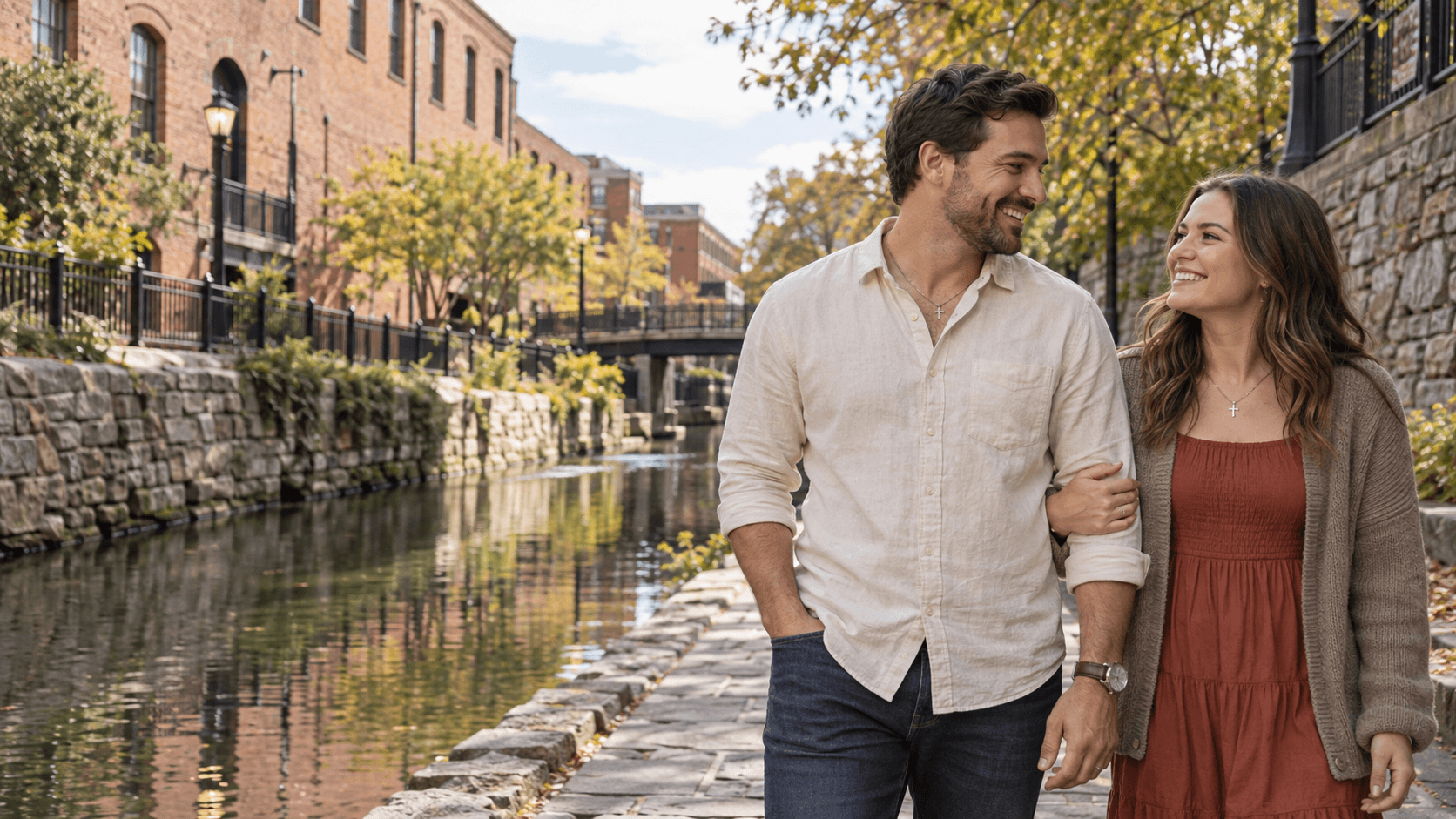 Couple with cross necklaces beside Richmond’s Canal Walk, with brick buildings behind them.